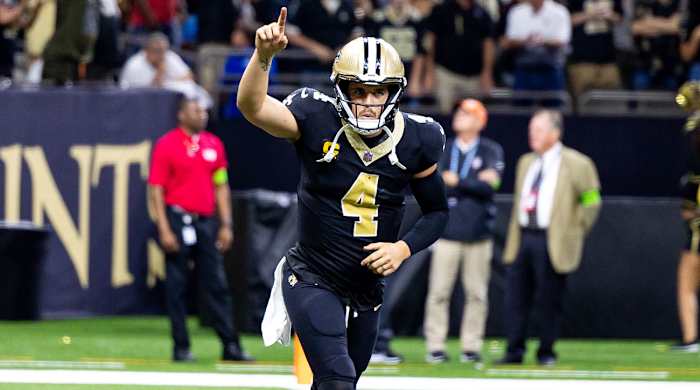 Saints QB Derek Carr points up to the sky with one hand as he runs
